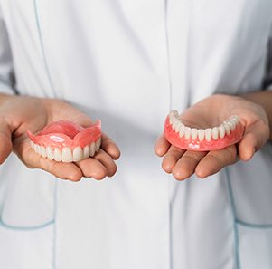 A dentist holding upper and lower dentures in his hands