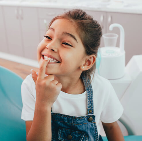 Young patient pointing to smile during children's dentistry visit