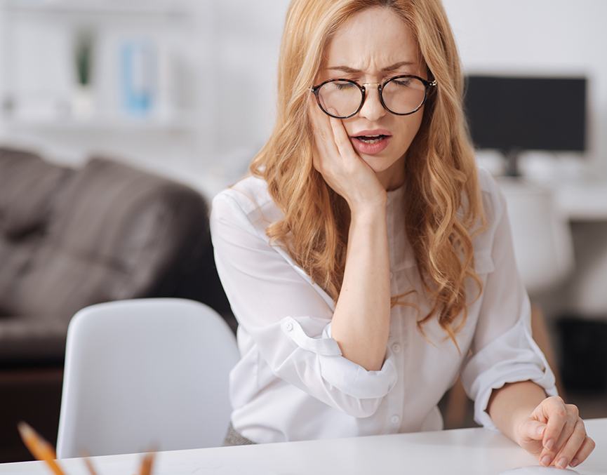 Woman sitting at table with pain from failed dental implant in Port Charlotte, FL