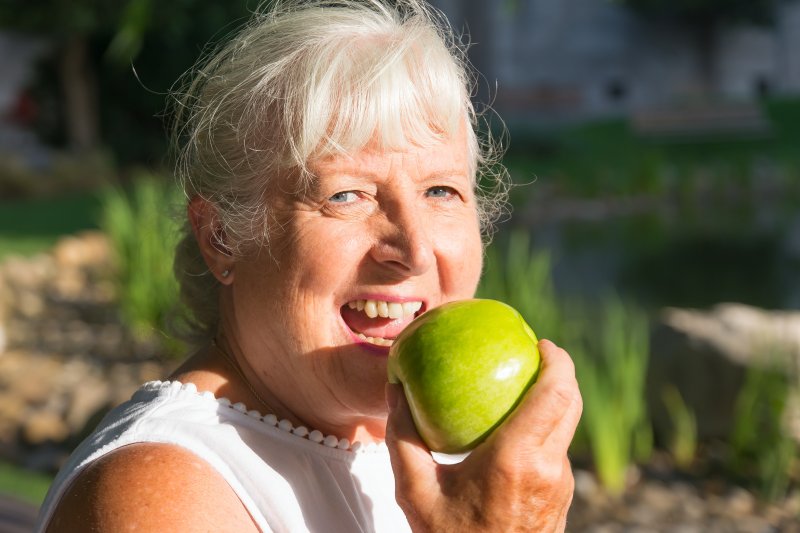 An elderly woman eating with dentures