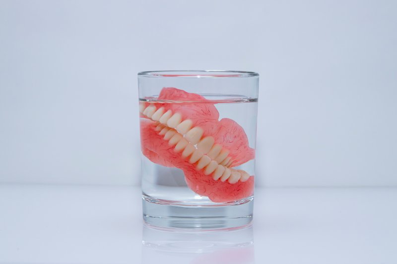 Dentures soak in glass of clear liquid